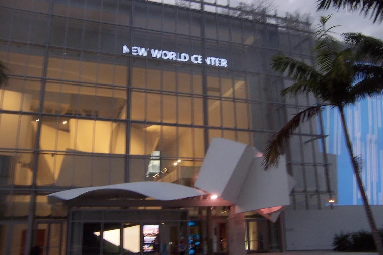 The glass front of Frank Gehry’s New World Center lit from within in the late afternoon, its sculptural white canopy over the entrance and palms alongside (2011).