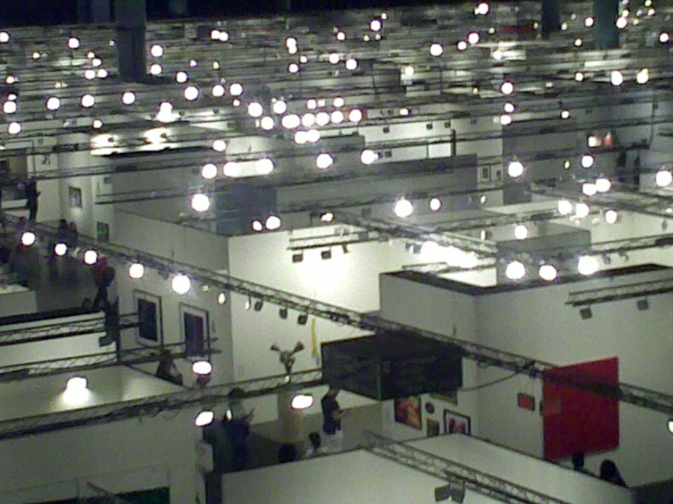 Looking down over the white-walled gallery booths of Art Basel Miami Beach under rows of bright lamps on the ceiling trusses (2009).