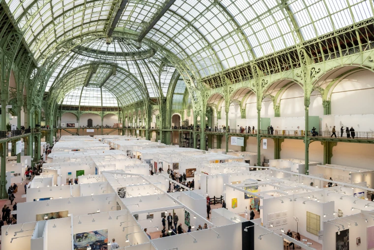 The nave of the Grand Palais seen from above, filled with white gallery booths beneath the green iron and glass roof (2025).