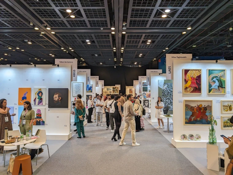 Visitors along an aisle of gallery stands hung with paintings during Dubai’s spring art week, at Art Dubai, an early-April engagement in the season calendar of The Mansa Court