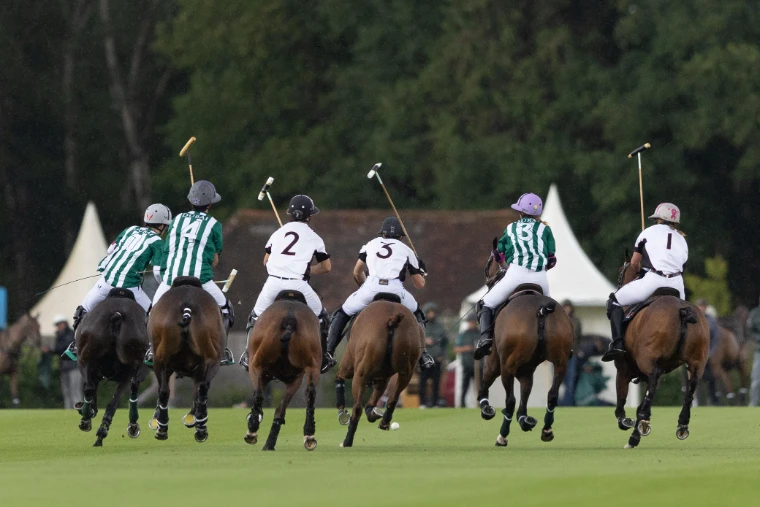Six players chase the ball downfield in the rain, the pavilion tents beyond (2025). The Cartier Queen’s Cup at Guards Polo Club, Windsor Great Park, in the season calendar of The Mansa Court