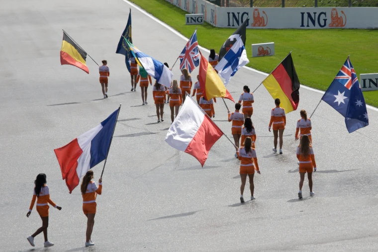 Women in orange uniforms carry national flags in a parade across the track before the race (2008).