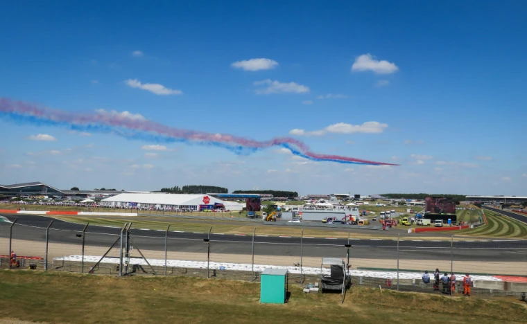 The Red Arrows trail red, white and blue smoke over the circuit before the race (2018).
