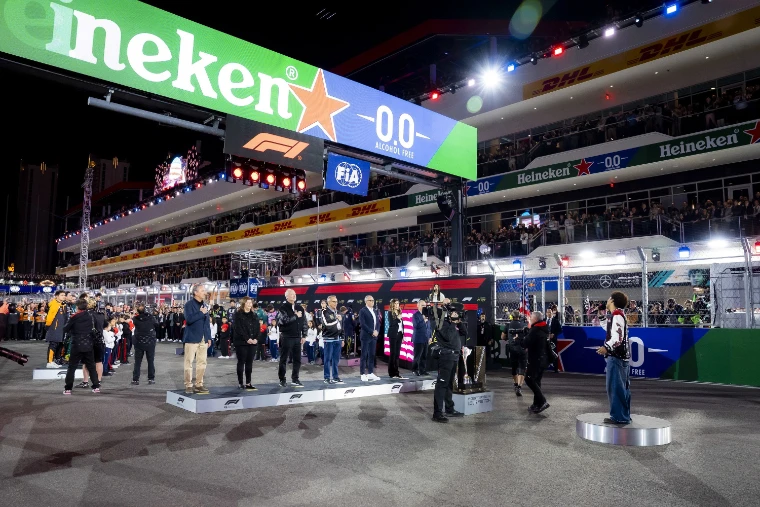 The start gantry and Heineken banner above the floodlit grid before the race, with guests on a stage and full grandstands along the pit building (2025).
