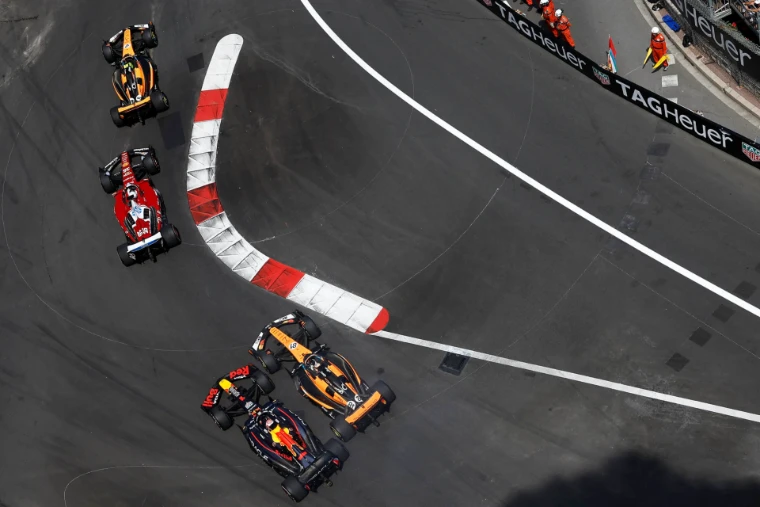 Cars thread the red and white kerbs of a chicane, seen from high above the street circuit. The Formula 1 Monaco Grand Prix on the streets of Monte Carlo, in the season calendar of The Mansa Court