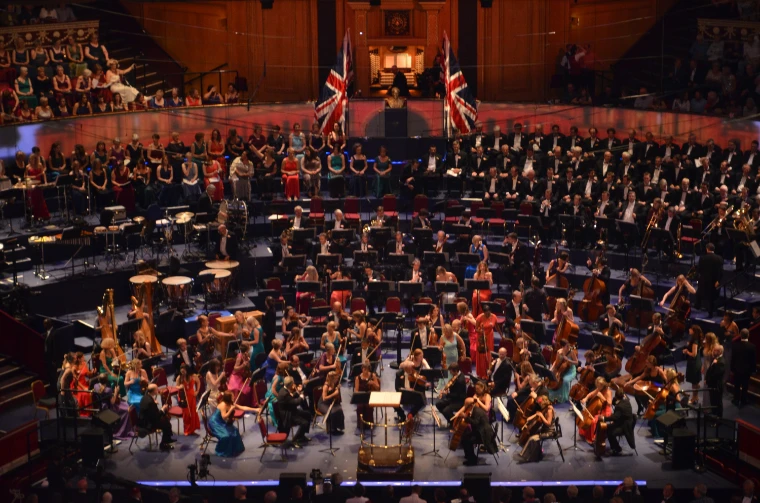 The orchestra in evening dress on the platform of the Royal Albert Hall, with the chorus behind and two Union Flags beneath the organ (2014).