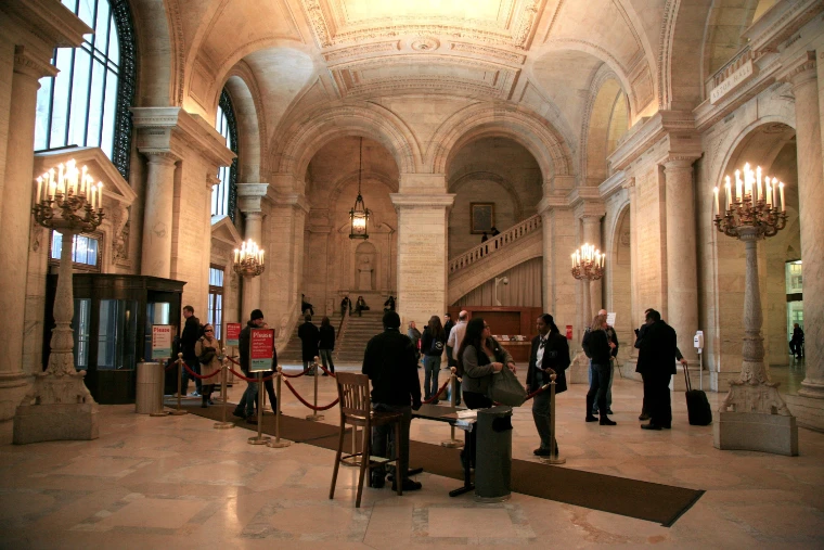The vaulted marble Astor Hall lit by tall candelabra, with visitors standing at the foot of the stairs (2011).