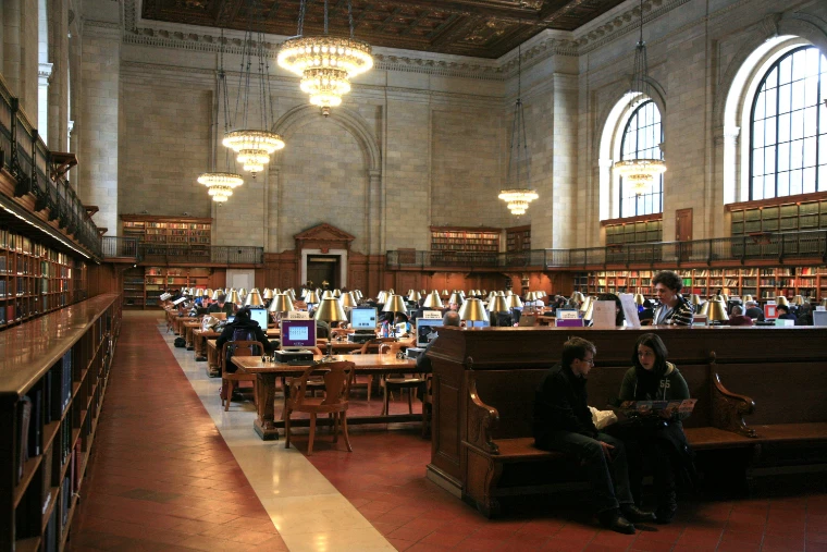 The long Rose Main Reading Room with chandeliers, tall arched windows, book-lined walls and rows of lamp-lit reading tables (2011).