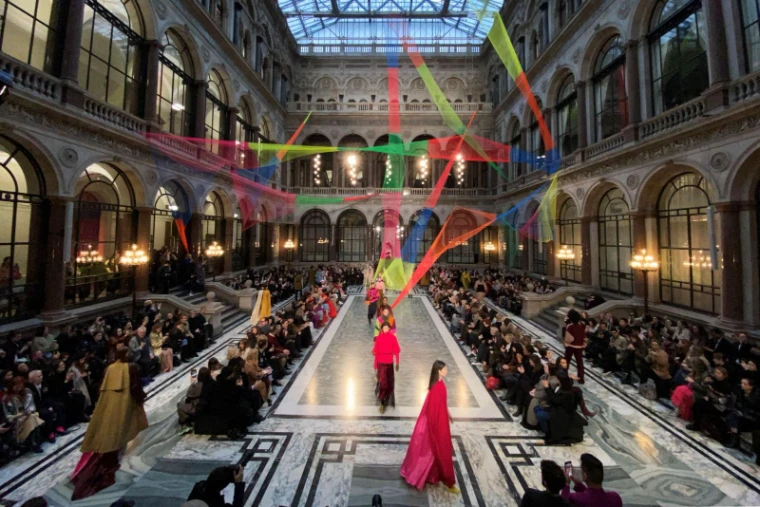 Models walking a marble runway beneath a coloured ribbon installation in a glazed Victorian atrium at London Fashion Week, an engagement in the season calendar of The Mansa Court