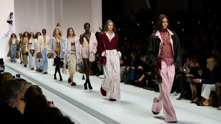 The full cast walking the finale in striped silk pyjama tailoring, lace and leather along a white runway at Milan Fashion Week, an engagement in the season calendar of The Mansa Court