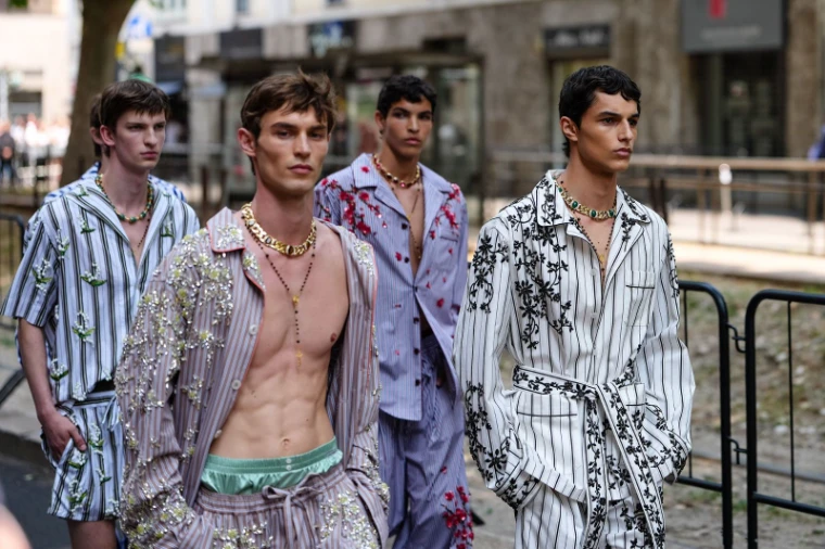 Models in embroidered striped pyjama dressing photographed on the pavement between shows at Milan Fashion Week, an engagement in the season calendar of The Mansa Court