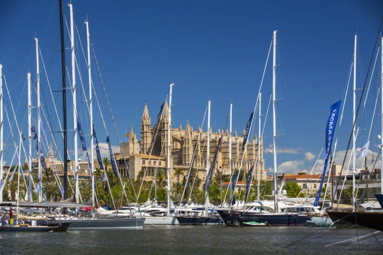 The tall masts of sailing superyachts framing the Gothic front of Palma Cathedral across the harbour, the setting of the Palma International Boat Show, Palma de Mallorca, a late-April engagement in the season calendar of The Mansa Court
