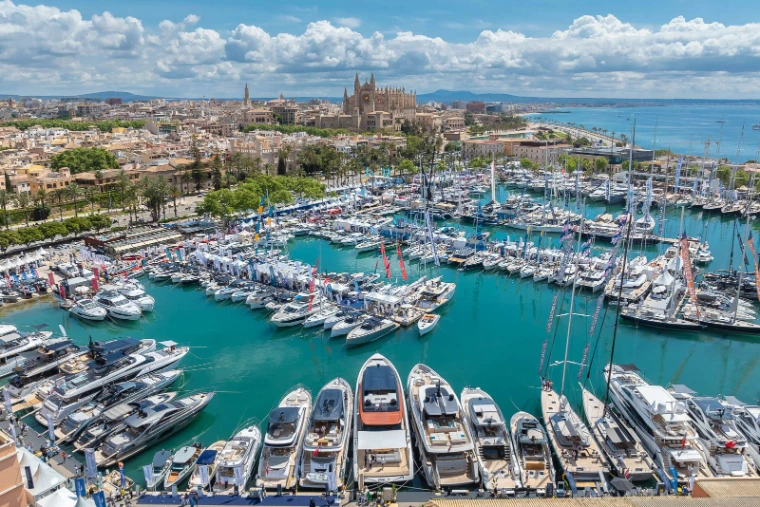 The show harbour crowded with yachts and white pavilions beneath Palma Cathedral and the old town at the Palma International Boat Show, Palma de Mallorca, a late-April engagement in the season calendar of The Mansa Court