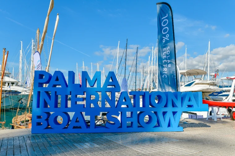 The blue lettered sign of the show on the quay before a forest of masts at the Palma International Boat Show, Palma de Mallorca, a late-April engagement in the season calendar of The Mansa Court