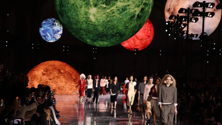 Models filing down a mirrored runway beneath vast suspended planets in a darkened hall at Paris Fashion Week, an engagement in the season calendar of The Mansa Court