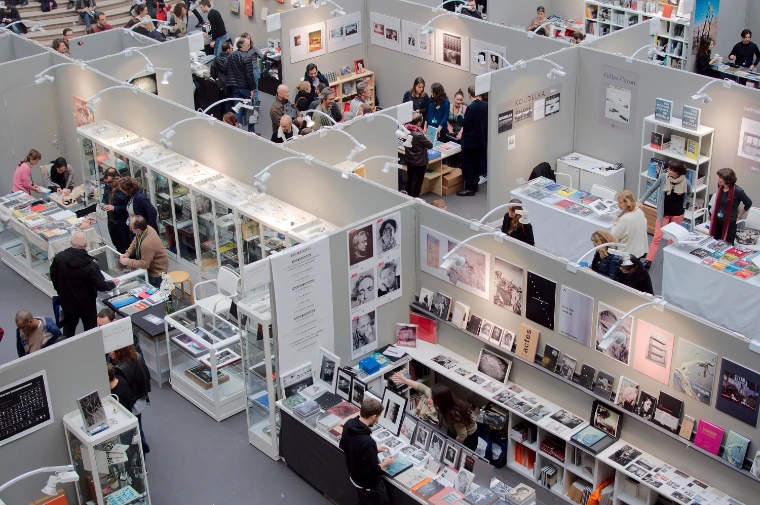 Looking down on the publishers’ stands at Paris Photo, visitors browsing tables and shelves of photobooks (2016).