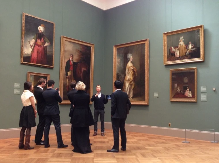 A small group in dark clothes listening to a guide before gilt-framed portraits on green walls in a museum gallery, for Private Gallery and Museum Tours, New York, an April morning in the season calendar of The Mansa Court