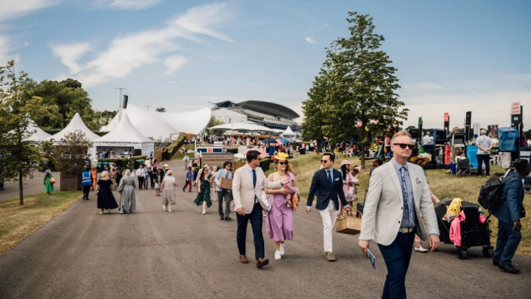 Racegoers in summer dress and hats walking between enclosures at Royal Ascot, an engagement in the season calendar of The Mansa Court