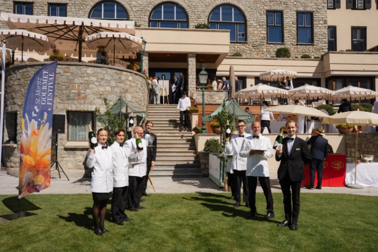 Sommeliers and waiters lined up on the lawn with champagne and glasses before the hotel steps at the St. Moritz Gourmet Festival, an engagement in the season calendar of The Mansa Court
