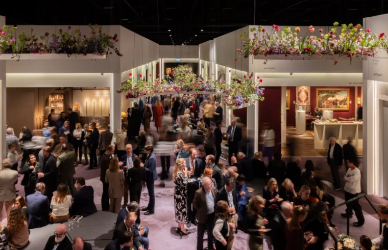 Collectors and dealers on the main floor of TEFAF Maastricht beneath suspended tulip installations, the vetted art and antiques fair in Maastricht, a March engagement in the season calendar of The Mansa Court