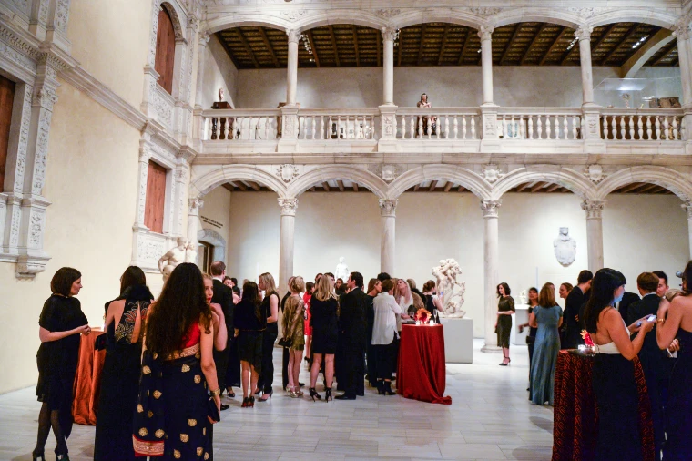 Guests in evening dress gather around cocktail tables in a two-storey Renaissance marble courtyard inside the Met (2014).