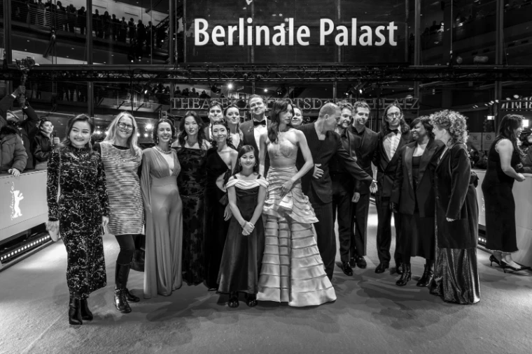 A film’s cast and crew gathered in evening dress for a portrait under the Berlinale Palast sign at The Berlinale, an engagement in the season calendar of The Mansa Court