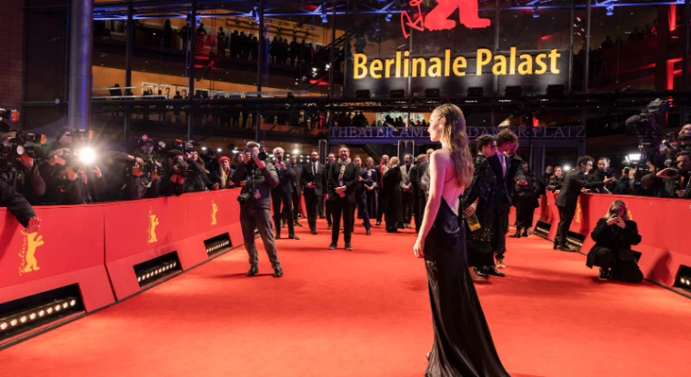 An actress in a black gown turning for the photographers on the red carpet beneath the Berlinale Palast sign at The Berlinale, an engagement in the season calendar of The Mansa Court