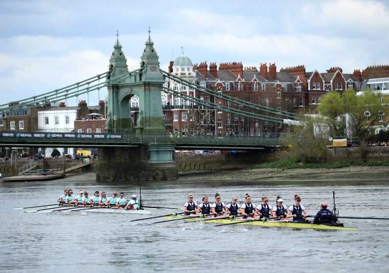 The women’s crews level below Hammersmith Bridge at The Boat Race, Oxford against Cambridge on the Thames, London, an engagement in the season calendar of The Mansa Court