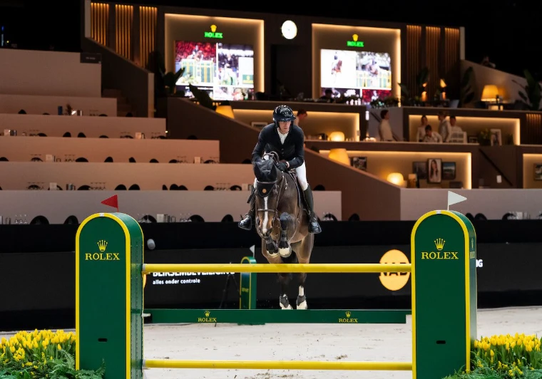 A horse and rider over a Rolex fence in front of the hospitality boxes at The Dutch Masters, ’s-Hertogenbosch, the March indoor show in the season calendar of The Mansa Court