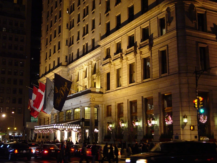 Flags hanging over the lit entrance of the Plaza Hotel at night, Christmas wreaths in the windows (2004).