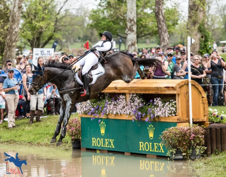 A horse and rider dropping over a flower-topped fence into the water on the cross-country course before the crowd at the Kentucky Three-Day Event, Lexington, a late-April engagement in the season calendar of The Mansa Court