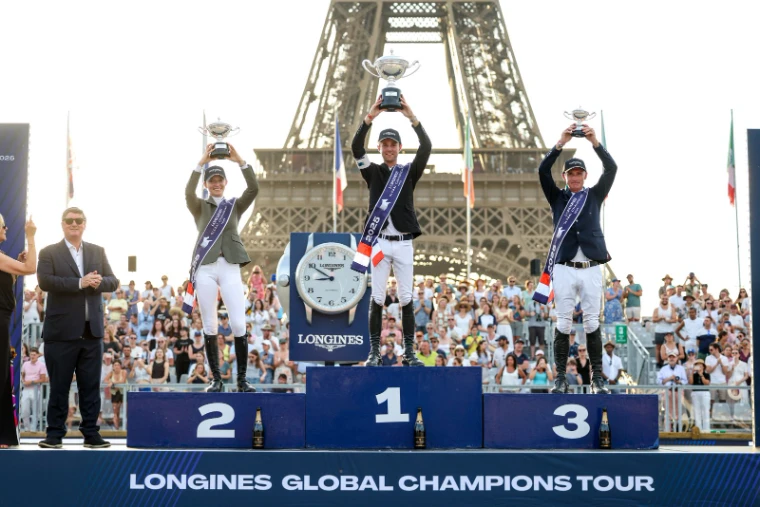 The three placed riders raising their trophies on the podium before the Eiffel Tower at the Longines Global Champions Tour Paris, a meeting in the season calendar of The Mansa Court
