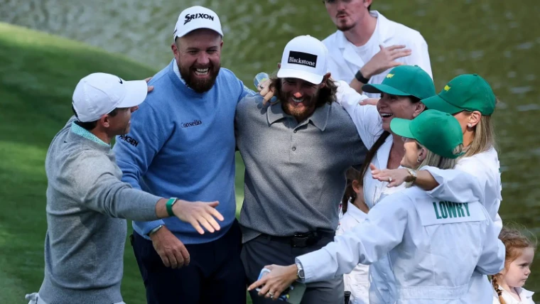 Players and their families in white caddie overalls celebrating at the water during the Par 3 Contest on the Wednesday of The Masters, Augusta, an engagement in the season calendar of The Mansa Court