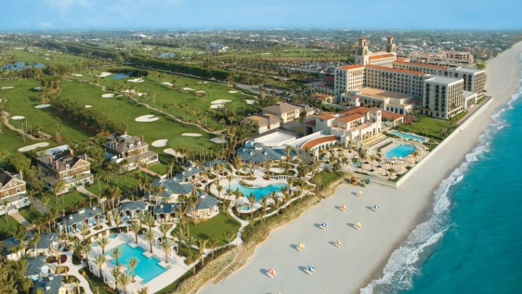 The island of Palm Beach, Florida, from the air during The Palm Beach Season, golf courses and pools running down to the beach, an engagement in the season calendar of The Mansa Court