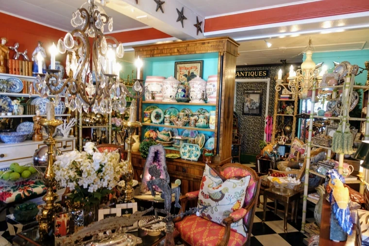 An antiques shop crowded with crystal chandeliers, majolica, blue-and-white porcelain and upholstered chairs, the trade behind The Palm Beach Show, West Palm Beach, an engagement in the season calendar of The Mansa Court