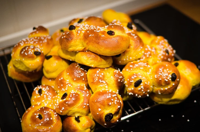 Freshly baked saffron buns with raisins and pearl sugar piled on a wire rack (2012).