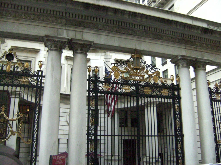 Marble columns and gilded wrought-iron gates of the Metropolitan Club, with an American flag in the courtyard beyond (2008).