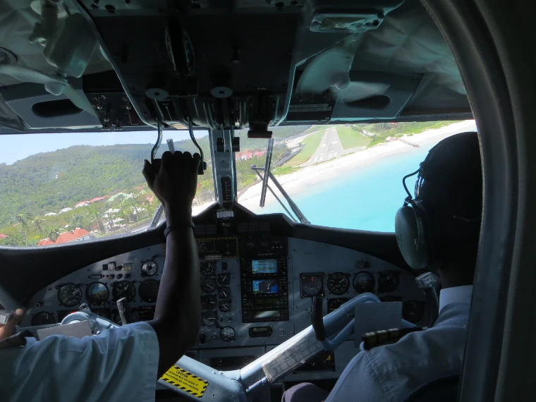 The view from the cockpit of a small aircraft descending towards the runway beside the turquoise water and white sand of St Jean (2014).