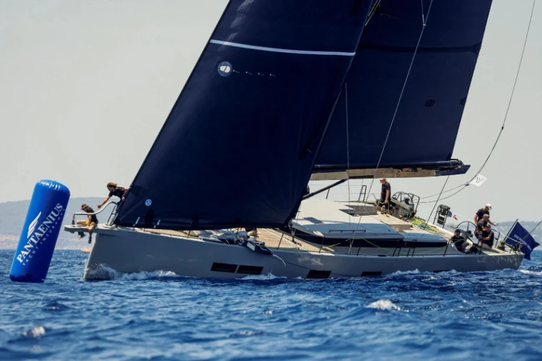 A dark-sailed sloop rounding the mark with crew on the rail at The Superyacht Challenge, the small-fleet regatta off Antigua, English Harbour, a March engagement in the season calendar of The Mansa Court