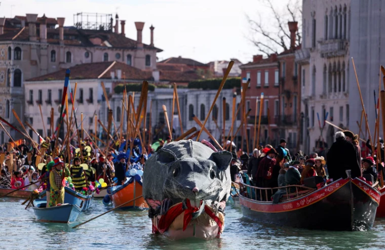 The great papier-mâché rat float leading the costumed rowing boats along the canal before the palazzi at The Venice Carnival, an engagement in the season calendar of The Mansa Court
