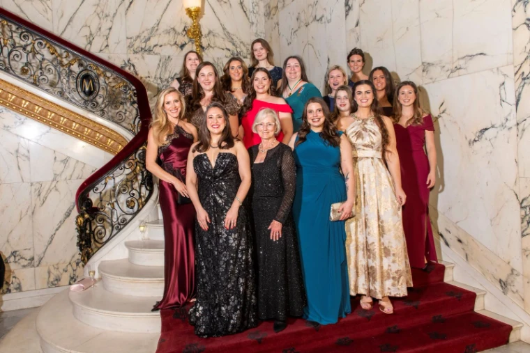Guests in evening gowns gathered for a portrait on the marble and gilt staircase at The Washington Birthday Ball, New York, an engagement in the season calendar of The Mansa Court