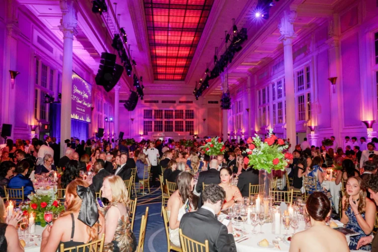 The columned ballroom lit for dinner with roses and candles at The Winter Ball, New York, an engagement in the season calendar of The Mansa Court