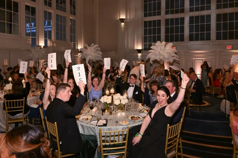 Guests in black tie raising numbered paddles during the appeal at The Winter Ball, New York, an engagement in the season calendar of The Mansa Court