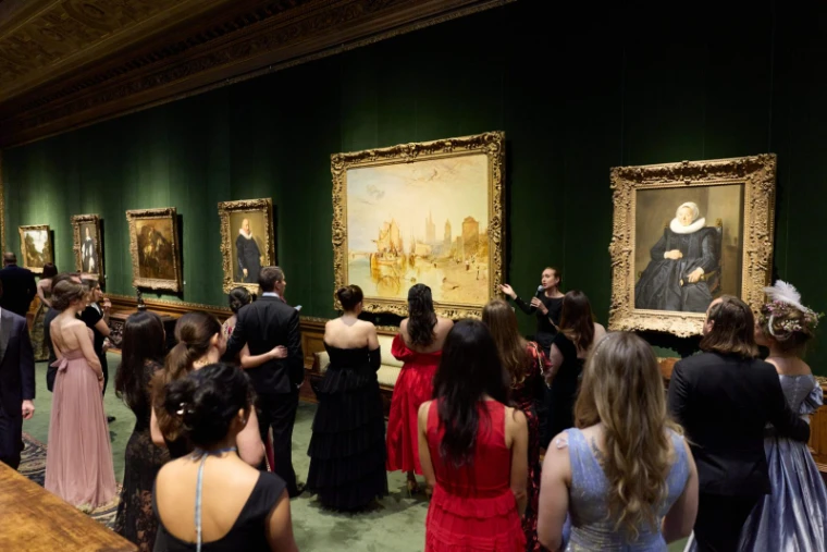 Guests in gowns and black tie gathered for a curator’s talk before a Turner in the green West Gallery at The Young Fellows Ball, The Frick Collection, New York, an engagement in the season calendar of The Mansa Court