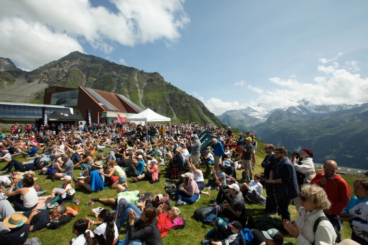 The audience on the grass at La Chaux applauds an open-air concert, the glaciers beyond (2023).