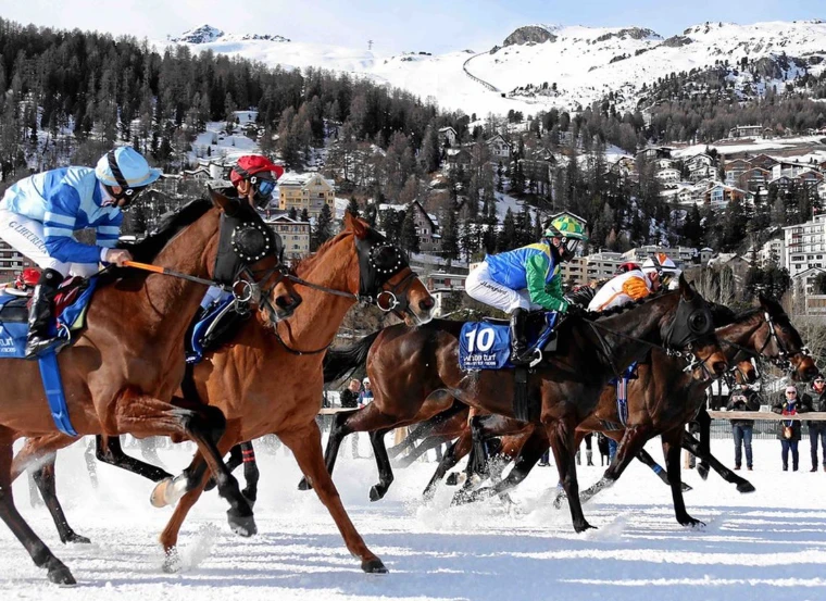 Runners passing at White Turf with the village of St. Moritz rising behind the frozen lake, an engagement in the season calendar of The Mansa Court